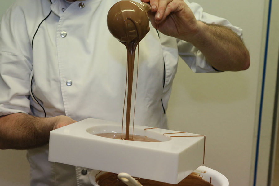 Le chocolat fondu, il faut ensuite le mouler. Les moules sont remplis, puis renverser pour laisser le chocolat superflu s'égoutter.